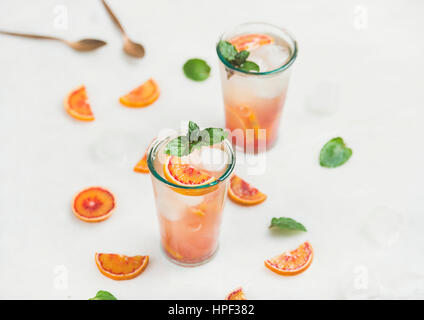 Orange sanguine limonade estivaux, avec de la glace et la menthe dans les verres, gris clair en arrière-plan, selective focus Banque D'Images
