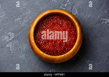 Caviar de saumon rouge dans le bol en bois sombre sur fond de pierre Banque D'Images