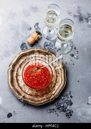 Caviar rouge dans bol en verre sur la glace et champagne sur fond de béton Banque D'Images