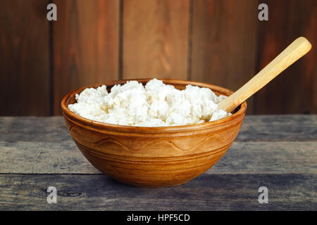 Produit Lait caillé dans Bol en céramique marron. Caillé dans cuvette d'argile. Fromage blanc frais dans un bol avec cuillère sur table en bois vintage Banque D'Images