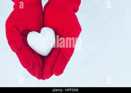 Coeur de neige dans les mains. Gants d'hiver rouge. Concept d'amour. Valentine's Day Greeting card with copy space. Valentine. Woman's hands en gants rouge Banque D'Images