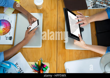 Vue supérieure de femmes graphistes utilisant téléphone mobile et tablette numérique sur 24 Banque D'Images
