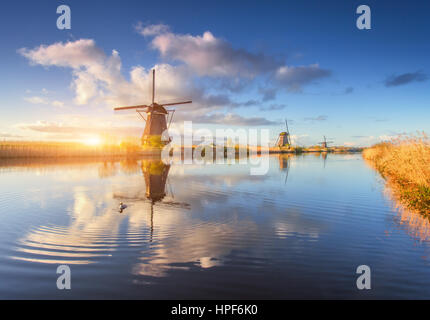 Les moulins à vent au lever du soleil. Paysage rustique avec de superbes moulins à vent hollandais près de l'eau canaux avec ciel bleu et nuages reflétée dans l'eau Banque D'Images