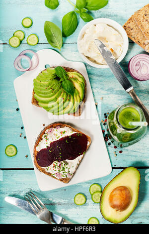 Sandwiches végétarien sain (avec avocat, tomate, concombre, oignon, betterave, fromage à la crème, les herbes et épices) sur fond rustique bleu Banque D'Images