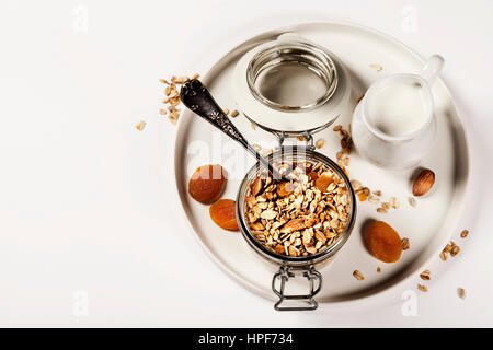 L'avoine avec granola maison de fruits et noix dans un bocal en verre sur fond blanc Banque D'Images