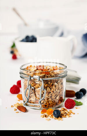 Granola fait maison (avec des fruits secs et noix) et un petit-déjeuner sain ingrédients - miel, lait et fruits rouges sur fond blanc Banque D'Images
