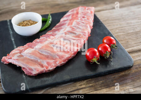 Côtes de boeuf, les piments, les tomates cerises et les graines de coriandre sur ardoise board Banque D'Images