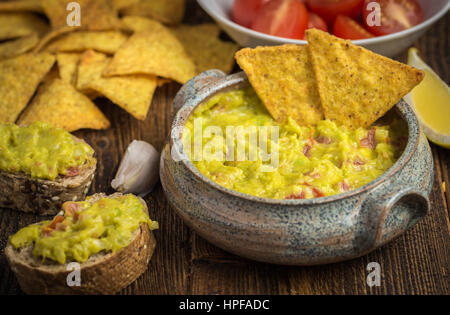 Guacamole en home bol conçu avec des croustilles sur le bureau en bois. Banque D'Images