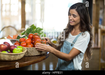 Femme choisissant de tomates fraîches le panier à l'épicerie Banque D'Images