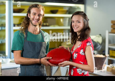 Portrait de vendeur et de fromage gouda holding client au comptoir dans un magasin de produits Banque D'Images