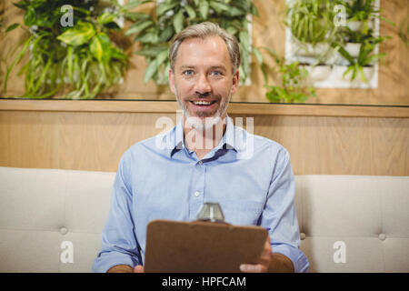 Portrait of smiling doctor holding clipboard in clinic Banque D'Images