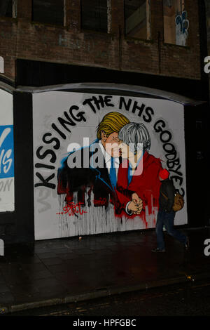 Bristol, Royaume-Uni. Feb 21, 2017. Un passant- par s'arrête pour examiner une nouvelle fresque qui a paru dans Stokes Croft à Bristol, nous montrant.Président Donald Trump et le Premier ministre britannique Theresa May. avec les mots ci-dessus.embrassant les N.H.S AU REVOIR. Une murale précédente au même endroit l'an dernier a montré l'atout de Donald et Boris Johnson dans une étreinte. Crédit : Robert Timoney/Alamy Live News Banque D'Images