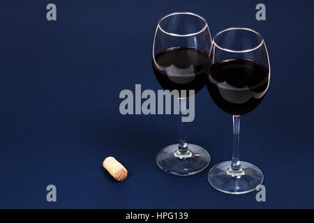 Vin rouge délicieux dans les verres isolé sur le bleu foncé Banque D'Images