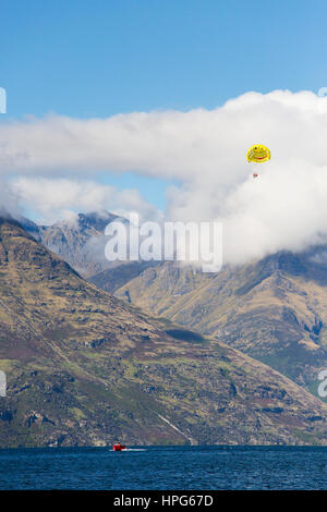 Queenstown, Otago, Nouvelle-Zélande. Le parapente sur le lac Wakatipu, Walter Peak enveloppée de nuages. Banque D'Images