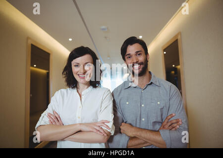 Portrait d'hommes et de femmes cadres d'standing with arms crossed in office corridor Banque D'Images