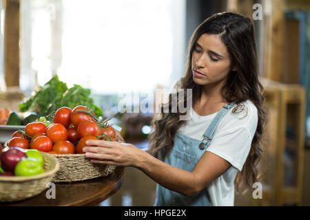 Femme choisissant de tomates fraîches le panier à l'épicerie Banque D'Images