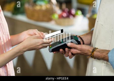 Close-up of woman making un paiement en utilisant la technologie NFC Banque D'Images