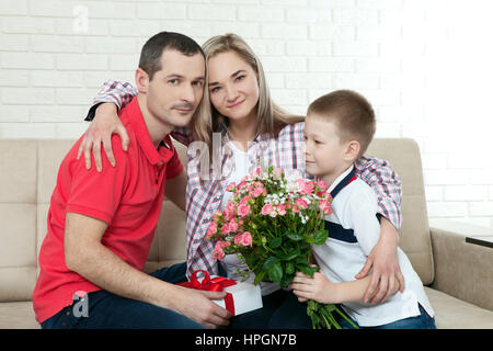 Fils caché de bouquet surprise maman sur la fête des mères. Femme, homme enfant des étreintes et des baisers Banque D'Images