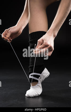 Vue partielle de la femme danseuse attachant sur noir chaussures de ballet Banque D'Images
