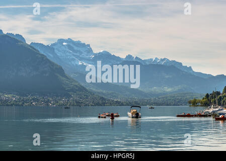 Belle vue sur le lac d'Annecy dans les Alpes françaises, un jour de printemps avec de la neige dans les montagnes et avec des bateaux au premier plan. Annecy, Haute Savoie Banque D'Images