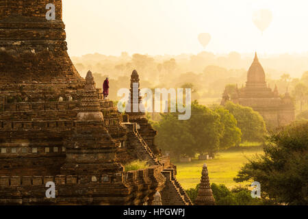 Monk et l'air chaud plus de ballons pagodes de lever du soleil à Bagan, Myanmar. Banque D'Images