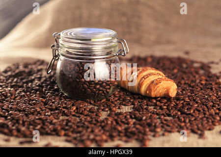 Les grains de café en pot et de savoureux croissants sur fond brun Banque D'Images