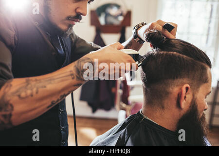 Gros plan de l'homme se coupe de la mode au salon de coiffure. Coiffeur mâle au service client, faire de l'aide coupe de machine et comb. Banque D'Images