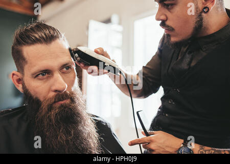 Jeune homme se coupe de la mode au salon de coiffure. Hairstylist donnant à décote élégant client au salon de coiffure. Banque D'Images