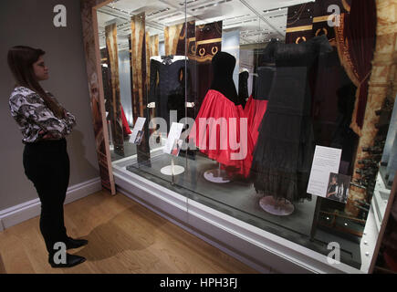 Une femme regarde (à partir de la gauche) un noir et blanc satin soie cocktail robe portée par la princesse de Galles pour un concert de Barbican Centre en 1989, un corsage de velours noir et rouge jupe de taffetas de soie, robe de soirée porté par Diana en visite officielle en Espagne en 1987 et d'une dentelle noire et magenta soirée soie robe portée par Diana en visite officielle en Allemagne en 1987, à l'aperçu de l'histoire de la mode Diana : son exposition au Palais de Kensington à Londres, qui célèbre le style de Diana, princesse de Galles. Banque D'Images