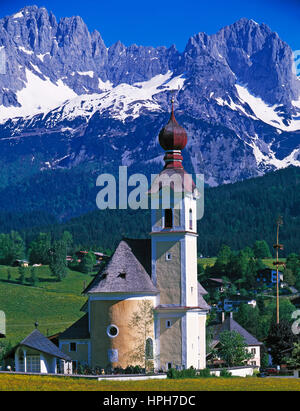 Les fleurs de printemps à aller avec son église d'oignon, Wilder Kaiser en arrière-plan, Tyrol, Autriche. Banque D'Images