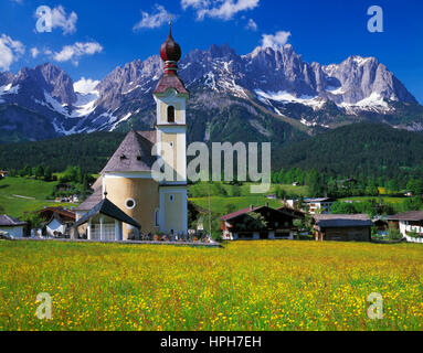 Les fleurs de printemps à aller avec son église d'oignon, Wilder Kaiser en arrière-plan, Tyrol, Autriche. Banque D'Images