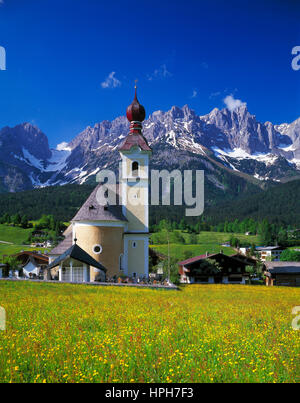 Les fleurs de printemps à aller avec son église d'oignon, Wilder Kaiser en arrière-plan, Tyrol, Autriche. Banque D'Images