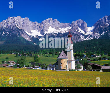 Les fleurs de printemps à aller avec son église d'oignon, Wilder Kaiser en arrière-plan, Tyrol, Autriche. Banque D'Images