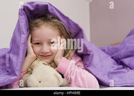 Maedchen liegt unter der Bettdecke - girl lying under bed cover, modèle publié Banque D'Images