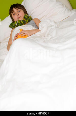 Junge Kranker liegt im Bett - garçon malade au lit, modèle publié Banque D'Images