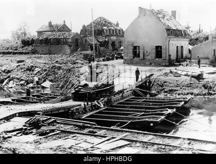 La propagande nazie, l'image montre des soldats de la Wehrmacht allemande dans une ville détruite pendant l'occupation du nord de la France - ici un réservoir est traversée d'un pont flottant. Pris sur Mai 1940. Un journaliste a écrit sur l'inverse de la photo, 'Le 10 mai, les Forces armées de l'Ouest a lancé une offensive majeure. Au point du jour la plus grande partie de l'armée allemande dans la région de l'Ouest ont franchi la frontière de l'Allemagne de l'Ouest dans une offensive, afin de prévenir une expansion imminente des hostilités à partir du territoire belge et néerlandais. Cela a commencé une victoire sans précédent de mars dans l'histoire du monde. - Notre pictu Banque D'Images