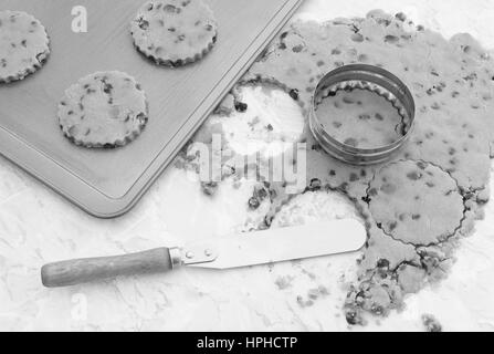 Baking cookies aux pépites de chocolat - cercles de coupe à partir de la pâte avec un emporte-pièce. Un couteau est utilisé pour transférer les formes de la plaque de cuisson. Banque D'Images