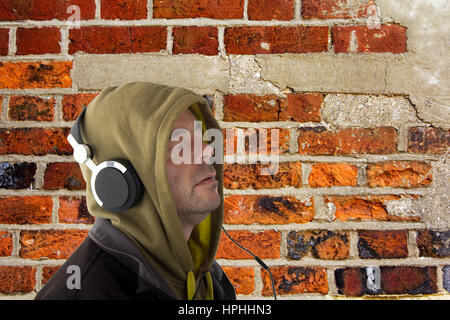 Man in hoodie listening to music on headphones Banque D'Images