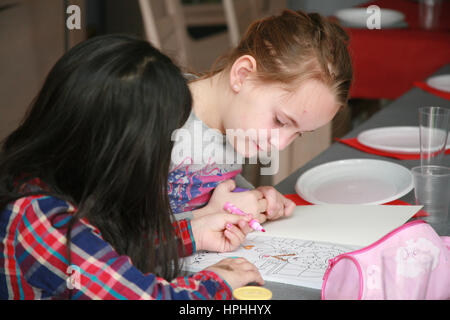 Deux jeunes filles s'assit à table de coloration. Banque D'Images