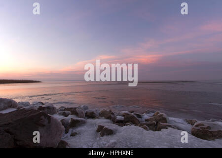Crimson rose coucher de soleil sur le lac près du pont en hiver avec des pierres Banque D'Images