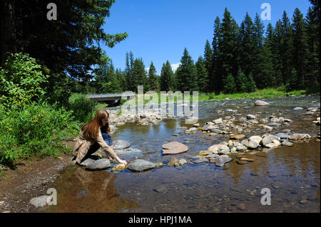 Jeune femme se trouve en dehors de la Gallatin River dans le Montana. Elle est pieds nus et seule avec ses pensées. Banque D'Images