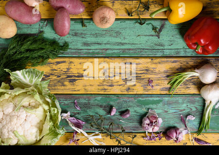 Alimentation saine alimentation végétale cadre. Matières premières fraîches, le brocoli, les pommes de terre, poivrons et des herbes sur fond en bois coloré. Copier l'espace, vue ci-dessus. Banque D'Images