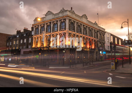 Bâtiment victorien dans un coin de la route à un brun froid crépuscule à Londres. Une longue exposition montrant les phares des voitures et bus comme des lignes de lumière Banque D'Images