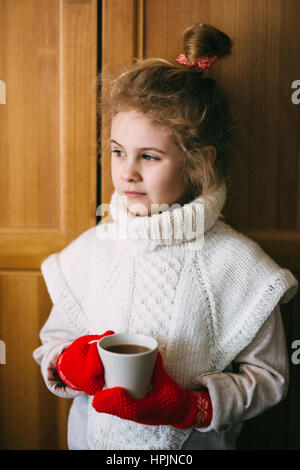 Cute blonde little girl holding à la vapeur chaude tasse de thé la photo en gros Banque D'Images