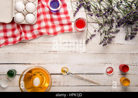 Vue de dessus les oeufs de poule en boîte avec les peintures et les fleurs violettes sur table en bois Banque D'Images