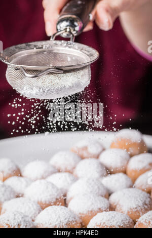 Saupoudrer de sucre en poudre sur des gâteaux Banque D'Images