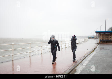 Homme et une femme bravant Doris Tempête sur la promenade à Colwyn Bay, au nord du Pays de Galles, Royaume-Uni Banque D'Images