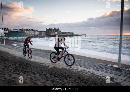 Aberystwyth, Pays de Galles, Royaume-Uni. 23 févr. 2017. Météo France : Deux jeunes femmes randonnée le long de la promenade au coucher du soleil à Aberystwyth après l'assaut de la tempête tempête Doris Doris a été le quatrième ouragan de l'hiver, et a été classé comme un 'bombe météorologique cyclogénèse explosive (des) par le Met Office Crédit photo : Keith Morris/Alamy Live News Banque D'Images