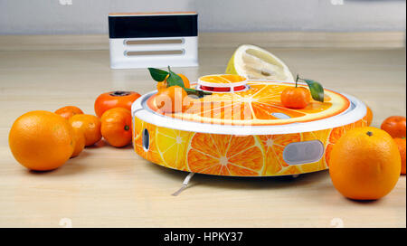 L'aspirateur robot automatisé des fruits orange stylisé sur un fond blanc station de charge Banque D'Images