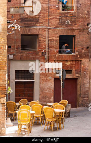 Homme assis dans la fenêtre à l'aide d'un téléphone mobile, Sienne, Toscane, Italie Banque D'Images